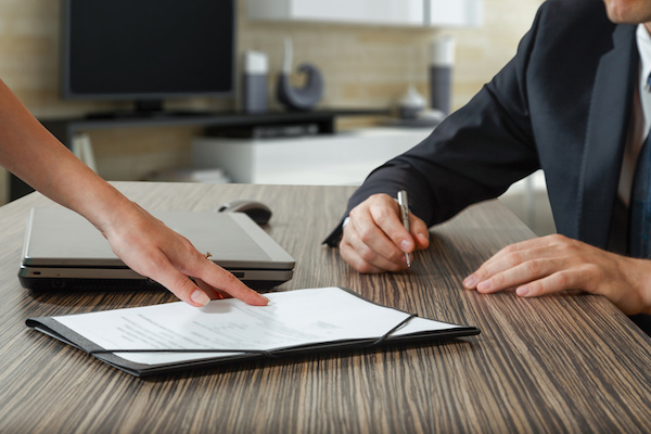 female hand pointing to businessman at signature place on a contract document